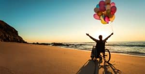 Lewis Reed Group | Wheelchair Accessible Vehicles | Person in wheelchair on beach with balloons